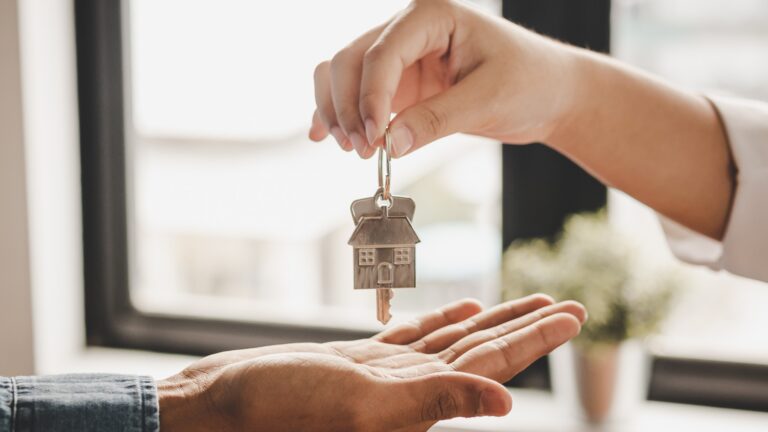 Nahaufnahme der Hand eines Immobilienmaklers, der die Schlüssel an einen Mieter übergibt
